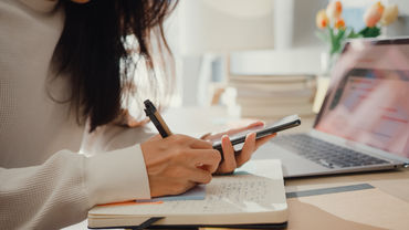 Frau trägt über Smartphone gebuchten Termin in ihren Kalender ein.